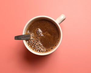 mug of coffee with a spoon on a pink background. View from above