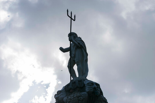 Estatua con cielo de fondo y tridente en la mano