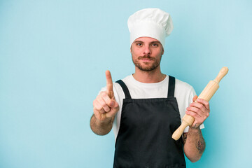 Young baker man isolated on blue background showing number one with finger.