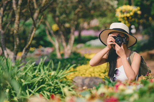 young girl taking photo flower in garden journey backpack.