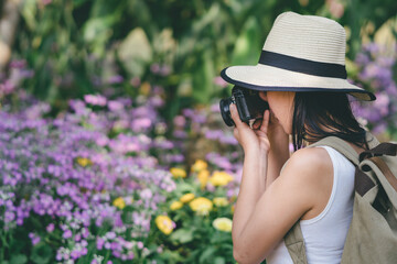 young girl taking photo flower in garden journey backpack.