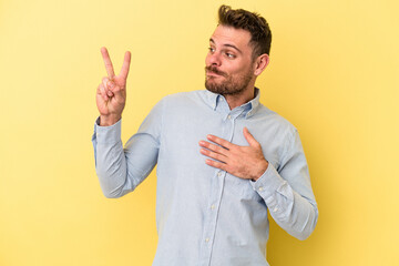 Young caucasian man isolated on yellow background taking an oath, putting hand on chest.