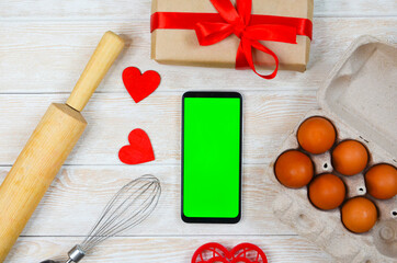 red festive ingrediens for cooking, valentines day eggs, rolling pin and whisk, cutter dish shape heart for baking cake flat lay, chroma key smart phone copy space