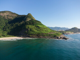 Fototapeta premium Aerial view of Prainha Beach, a paradise in the west side of Rio de Janeiro, Brazil. Big hills around. Sunny day at dawn. Greenish sea. Drone Photo