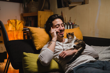 man laying on sofa at his home and talking on mobile phone