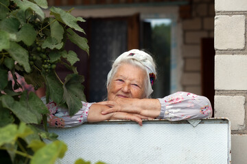 Portrait of a very old woman walking in her garden with flowers in summer. Grandparents day....