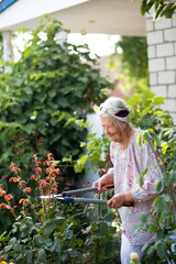 Senior woman with gardening tool working in her backyard garden