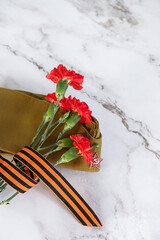 Victory Day, 9 May holiday concept. George Ribbon, carnation flowers and soviet military cap on...