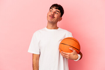 Obraz premium Young mixed race man playing basketball isolated on pink background dreaming of achieving goals and purposes