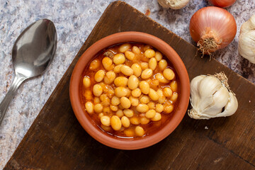 Hot turkish bean stew on wooden background. Ispir beans cooked in a casserole - Kuru Fasulye. Top view
