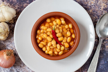 Hot turkish bean stew on wooden background. Ispir beans cooked in a casserole - Kuru Fasulye. Top view