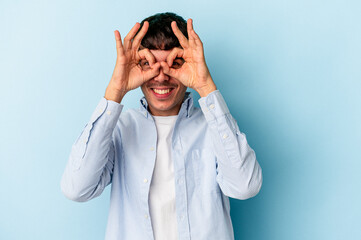 Young mixed race man isolated on blue background excited keeping ok gesture on eye.