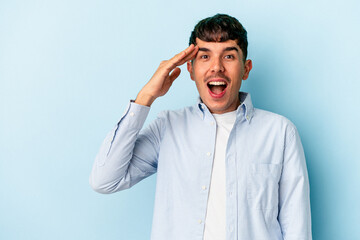 Young mixed race man isolated on blue background shouts loud, keeps eyes opened and hands tense.