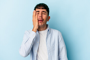 Fototapeta premium Young mixed race man isolated on blue background tired and very sleepy keeping hand on head.