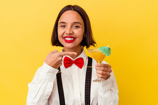 Young Bartender Woman Holding A Cocktail Isolated On Yellow Background