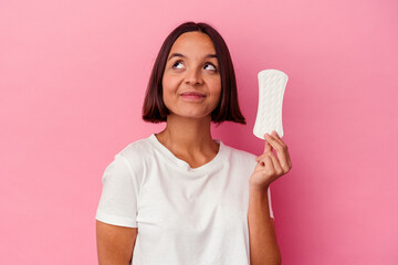 Young mixed race woman holding a compress isolated on pink background dreaming of achieving goals...