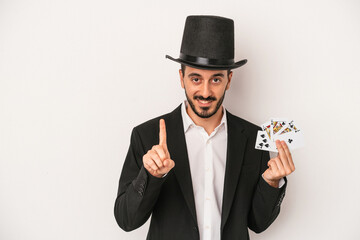 Young magician man holding a magic card isolated on white background showing number one with finger.