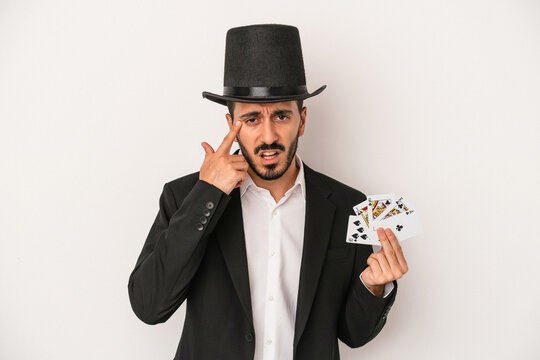 Young magician man holding a magic card isolated on white background showing a disappointment gesture with forefinger.
