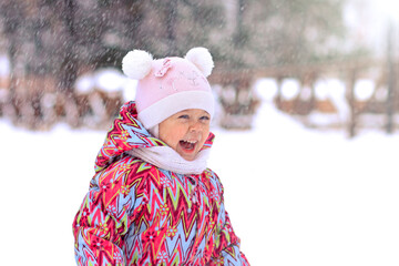 Happy and smiling child kid caucasian little girl of 2 years laughing looking at snow in winter snowy park