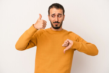 Young caucasian man isolated on white background showing thumbs up and thumbs down, difficult...