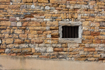 Ancient wall and  quadrat window with metal bars