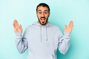 Young caucasian man isolated on blue background receiving a pleasant surprise, excited and raising hands.