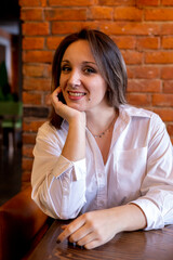 Young woman sits in a cafe at a table on the couch. Waiting for breakfast.