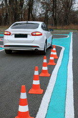 Modern car on driving school test track with traffic cones