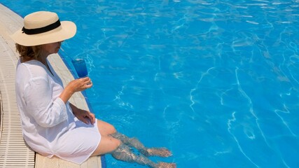 Senior woman relaxing in the hotel swimming pool. People are enjoying their summer vacation. All...