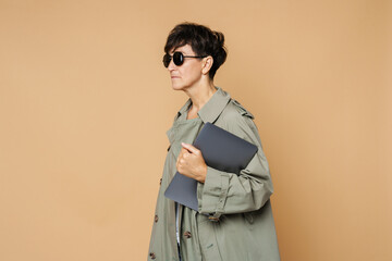 Fototapeta premium Mature european woman wearing sunglasses posing with laptop