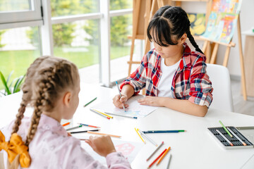 Multiracial girls drawing during class in art school