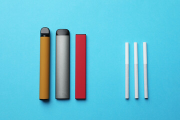 Electronic and regular cigarettes on light blue background, flat lay