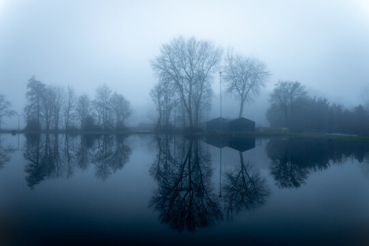 Reflection in the water on a foggy and dark day at sports park Elsgeest in the village of Voorhout (Teylingen) in the Netherlands.