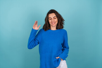 Woman in a blue knitted sweater and natural make-up, curly short hair, with an infectious radiant...