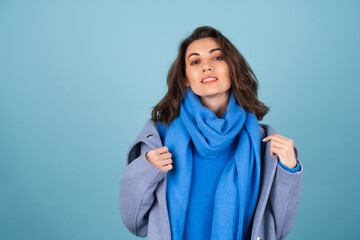 Spring autumn portrait of a woman in a blue knitted sweater, scarf and gray coat, posing...