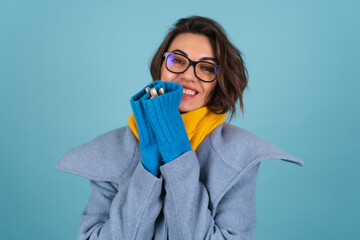 Spring autumn portrait of a woman in a blue knitted sweater, glasses, a yellow bright scarf and a...