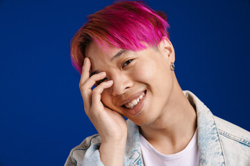 Asian boy with pink hair smiling and covering his face