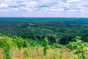 Fototapeta na wymiar Natural beautiful landscape. View from mountain on forest valleys against blue cloudy sky. National park, layered Hills. Lookout point. Deciduous and coniferous forest