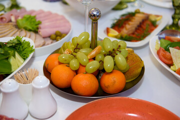 Fototapeta na wymiar Fruits on the festive table. Oranges and grapes on a platter.