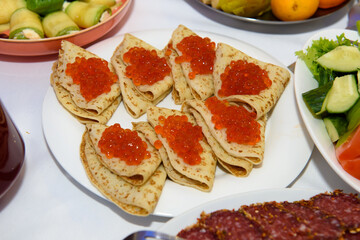 Red caviar on pancakes. Russian traditional dish on a plate.