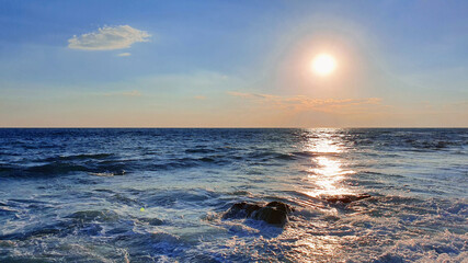 Colorful sunset with large sun under the sea waves.