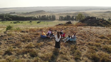 Confident female speaker conducts lecture, teaching a multinational team interesting techniques at a group meeting in nature, air view. Aerial. Coworking concept