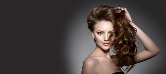 Model with long hair. Waves Curls Hairstyle. Hair Salon. Updo. Fashion model with shiny hair. Woman...