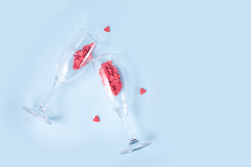 Two champagne glasses with red heart shaped candy. Valentine's Day concept.