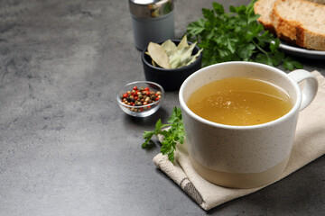 Hot delicious bouillon in cup on grey table. Space for text