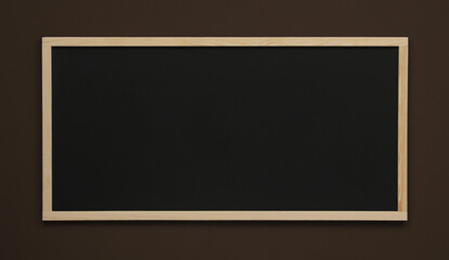 Clean black chalkboard hanging on brown wall
