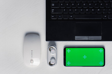 Flat lay shot of gadgets and mobile devices in white background. Smartphone green screen mockup