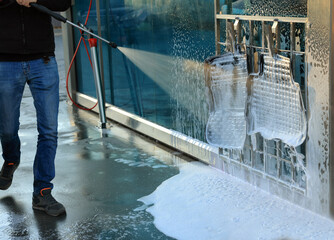 Man cleaning auto mats with high pressure water jet at self-service car wash, closeup