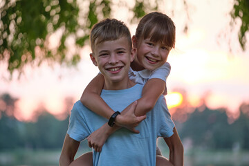 Happy siblings hugging lovingly in summer park. Young children brother and sister embracing each...