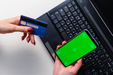 Close up image of woman hands using smartphone blank green screen mockup and holding credit card